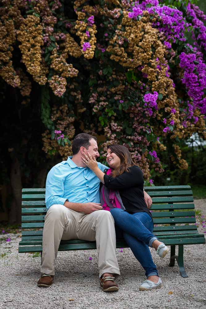 Sitting together down on a bench with bright colorful flowers in the back