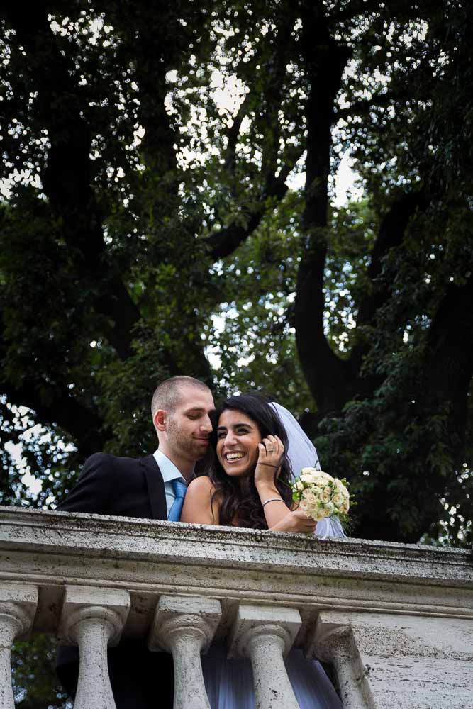 Married couple standing underneath a green tree