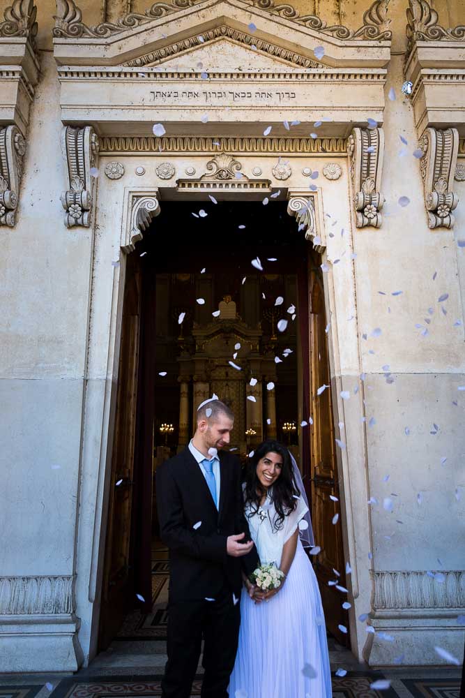 Walking outside the synagogue after getting married with petals