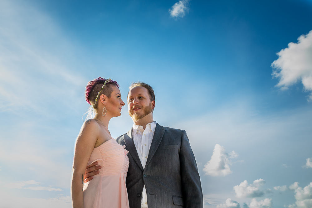 Portrait picture of a couple in wedding attire surrounded by blue sky