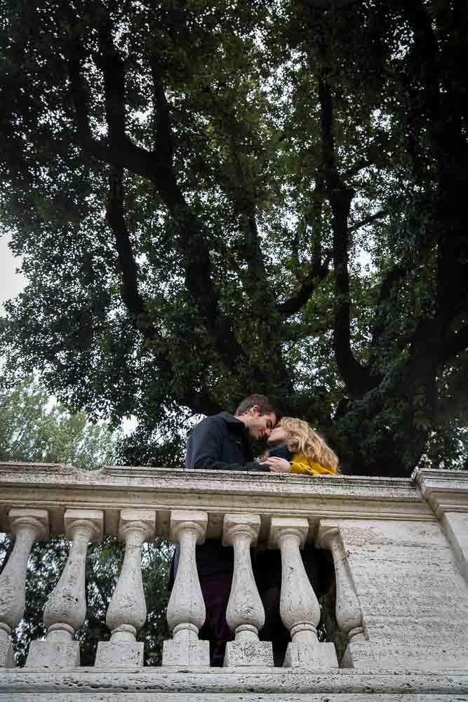 Couple kissing under a tree in a park