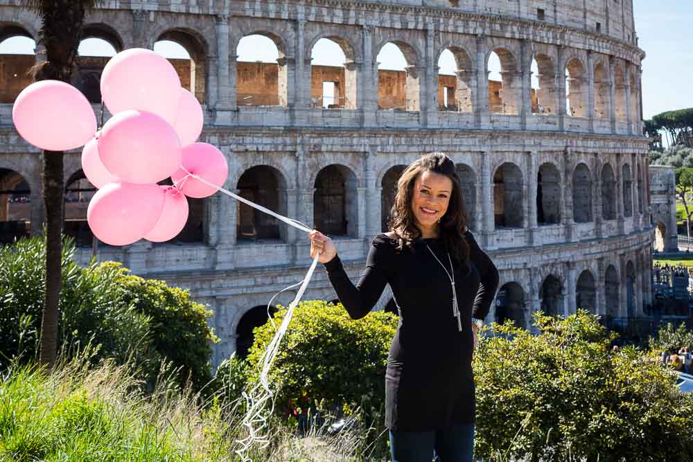 Woman holding up prenatal balloons at the Roman Colosseum during a photo session