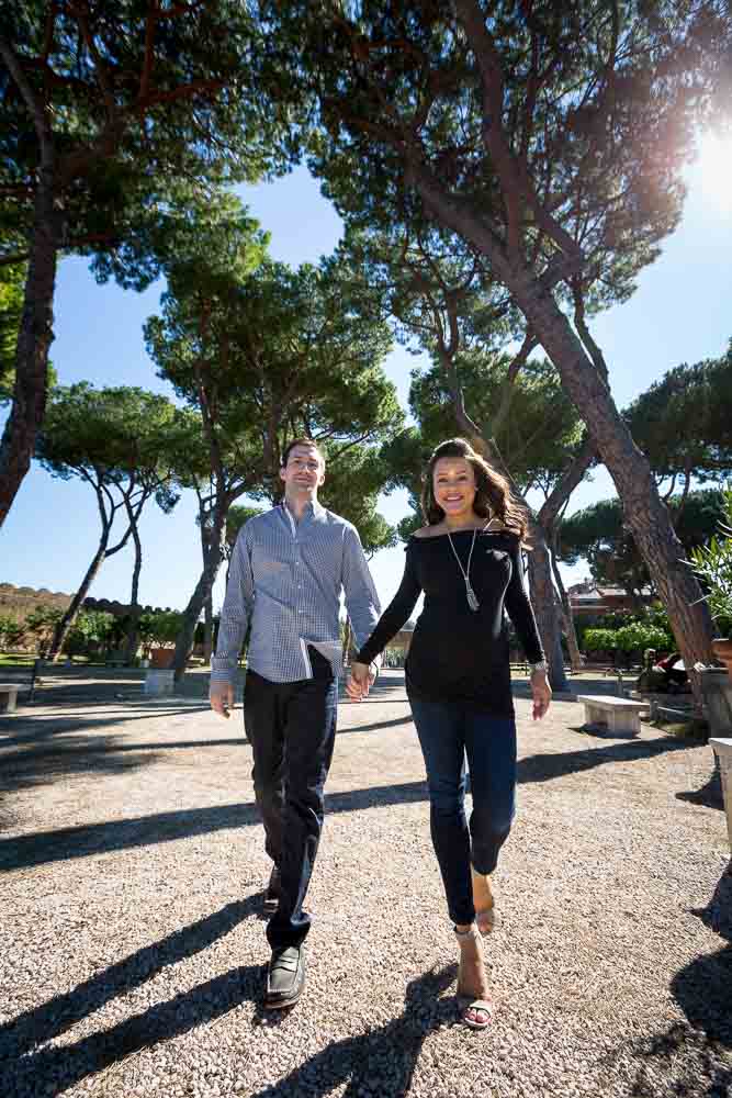 Walking image under Mediterranean pine trees found in a park during a maternity photo session