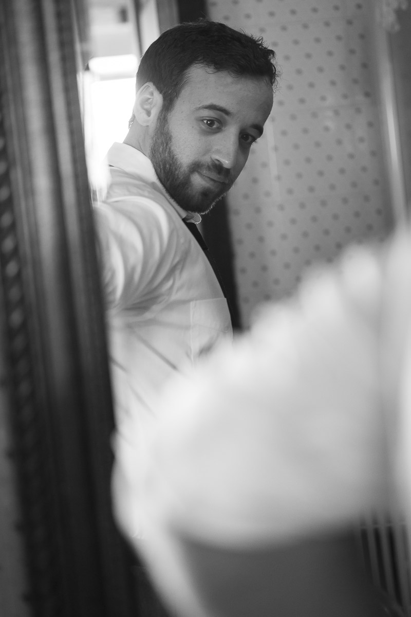 Groom looking in to the mirror in a black and white photo