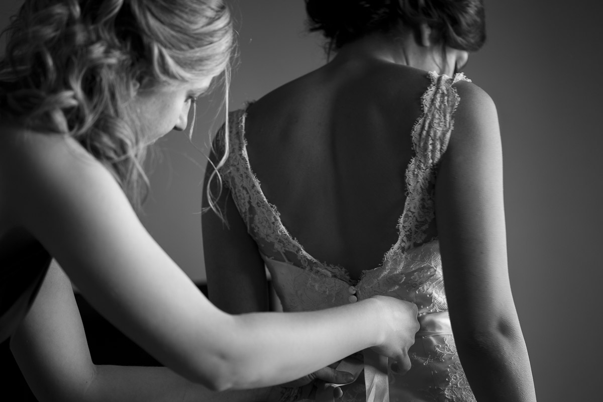 The closing of the wedding dress by a bridesmaid in black and white picture