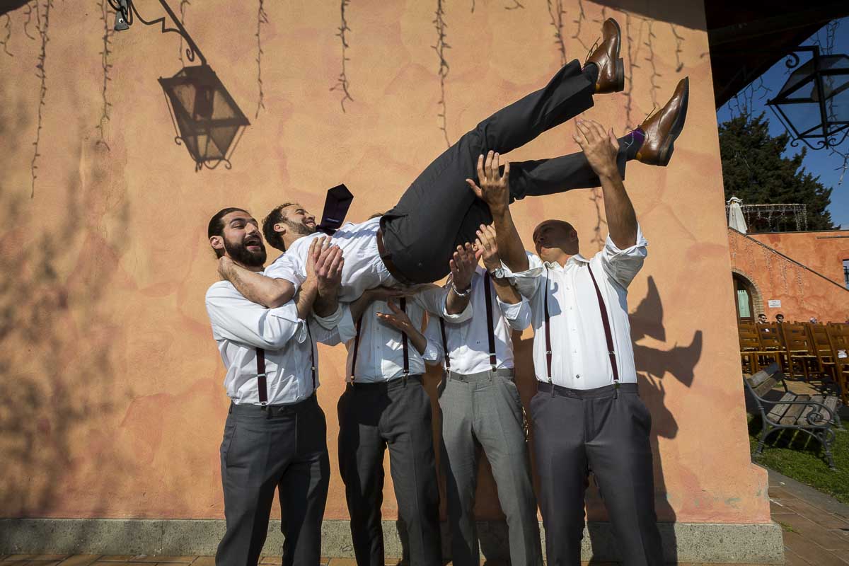 Groomsmen throwing the groom in the air