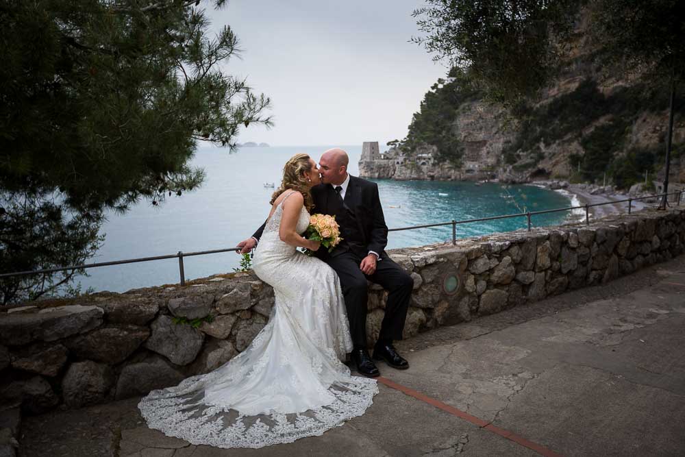 Just married honeymoon sitting down kissing. wedding photographer positano