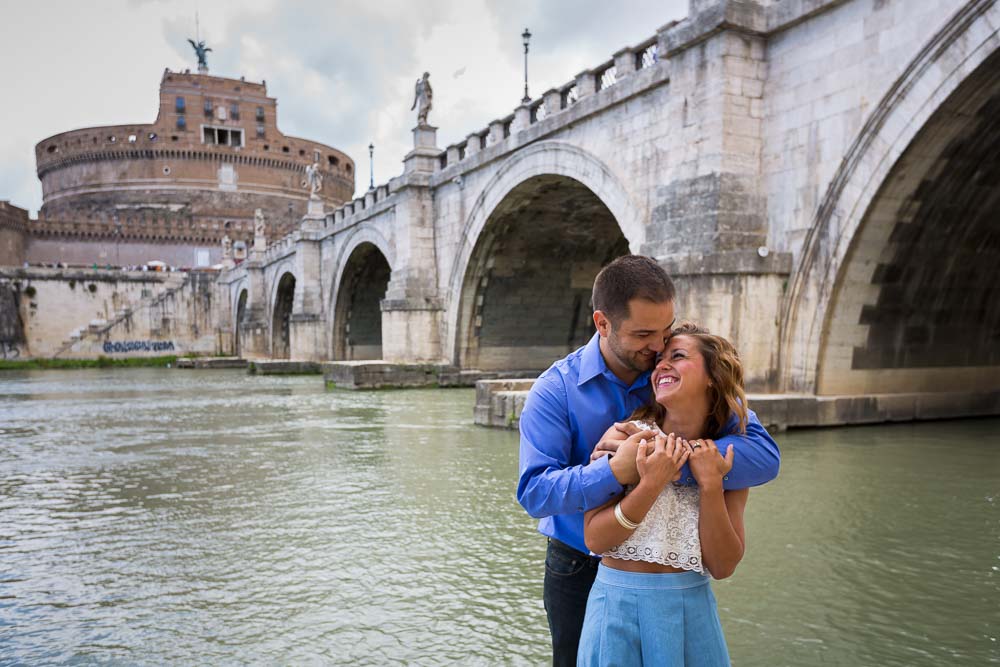 Couple embracing under the Castel Sant'Angelo bridge by the Tiber river bank in Rome Italy