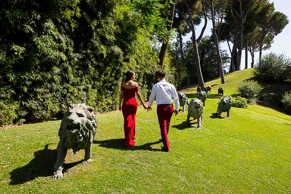 Couple walking hand in hand up a grass hill with lion statues