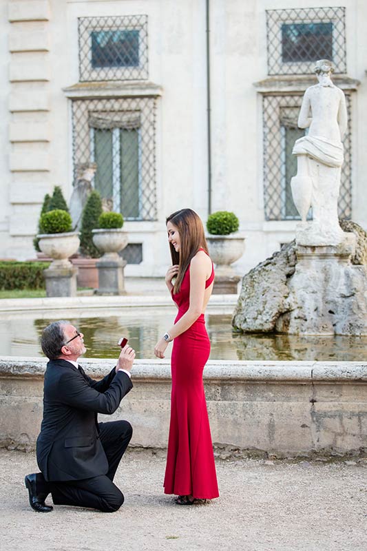 Surprised by the proposer's marriage request next to a scenic water fountain in Villa Borghese park