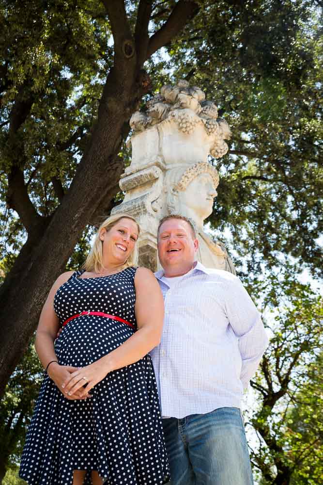 Couple standing underneath a statue in a park