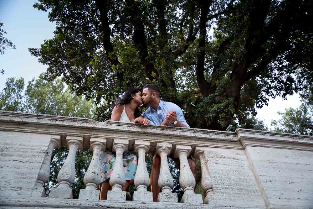 Couple in love kissing underneath a large tree in a park