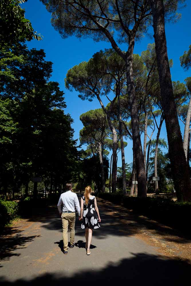 Walking hand in hand underneath Italian Mediterranean pine trees above