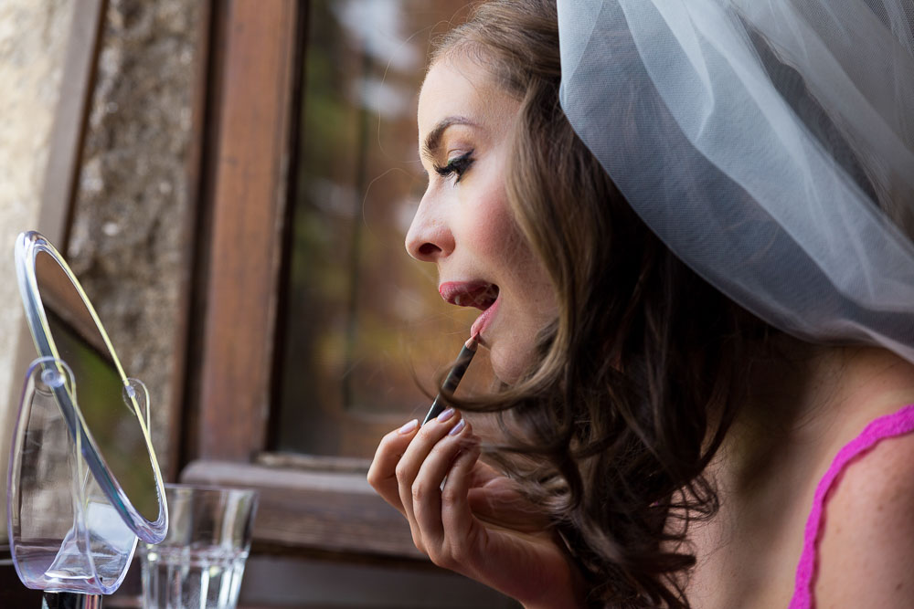 Bride putting on make up by the window