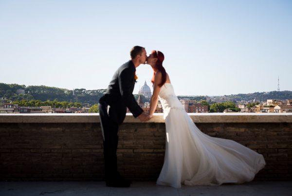Kissing while framing Saint Peter's dome in the far distance. Rome, Italy