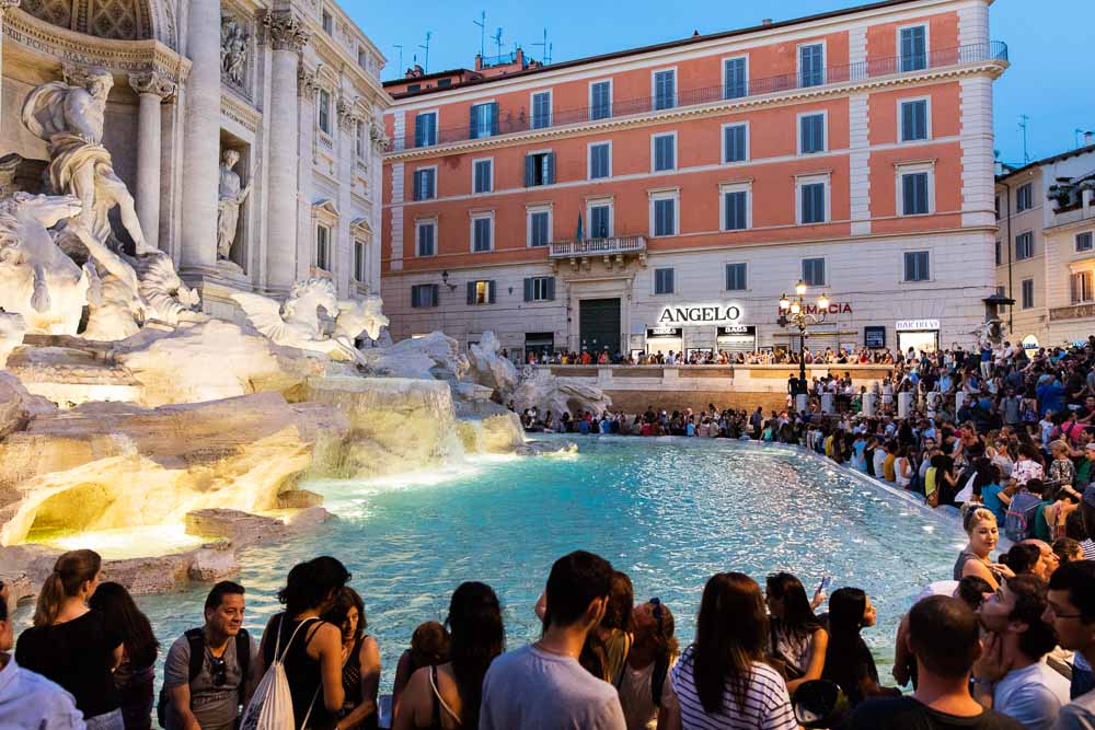 The crowd around fontana di trevi at night in the summer time