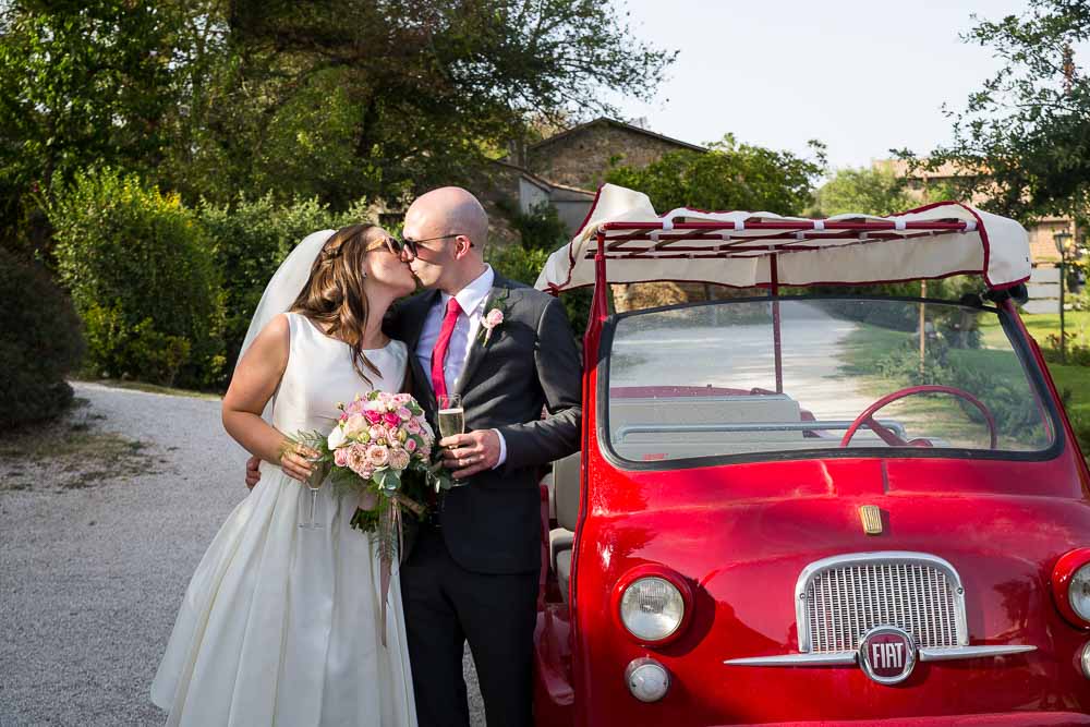 Bride & groom portrait by a bright red fiat vintage car