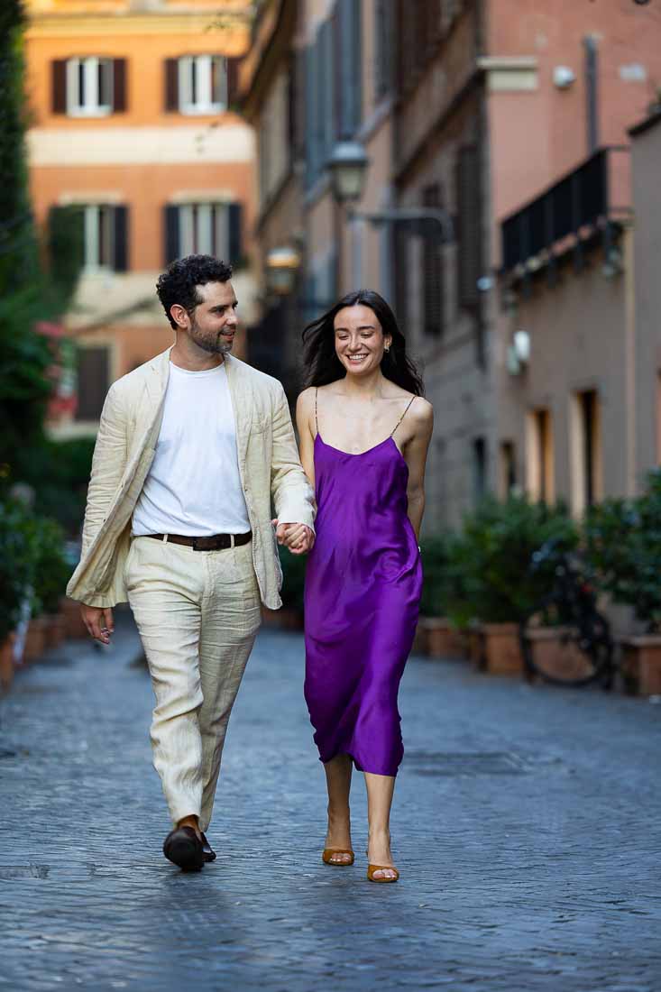 Walking hand in hand on cobblestone alleyway which is roman typical scenery captured with a long tele lens 