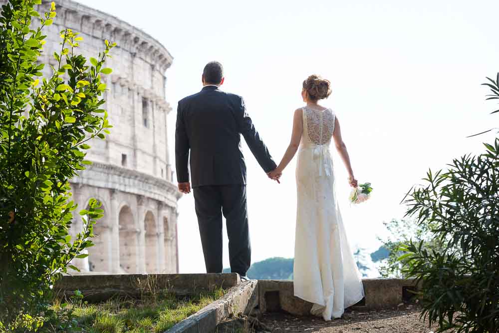 Looking at the Colosseum wearing wedding attire