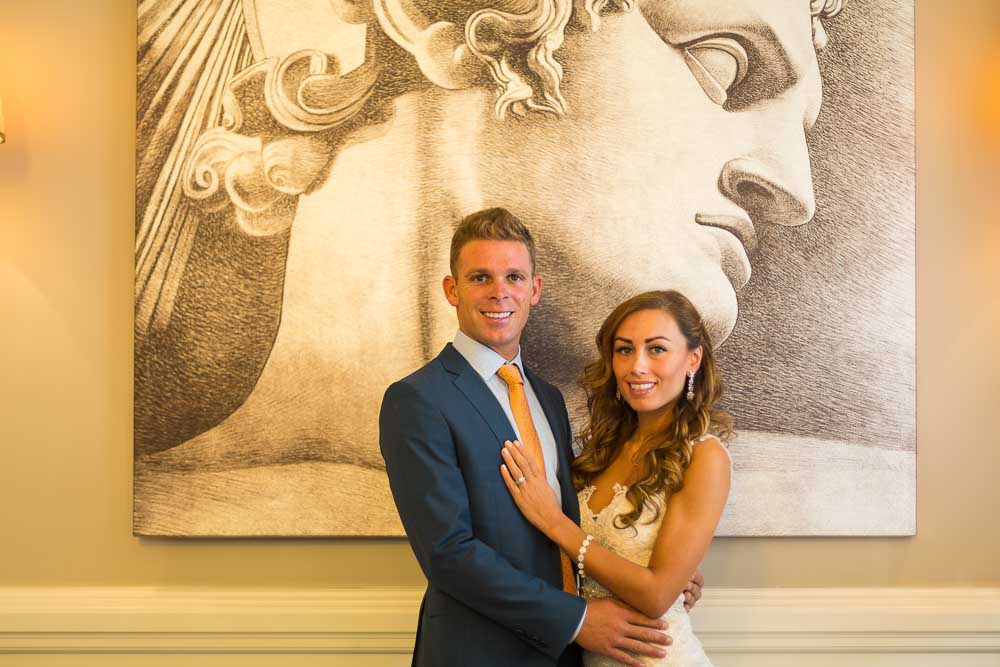 Newlyweds posing under a roman picture painting