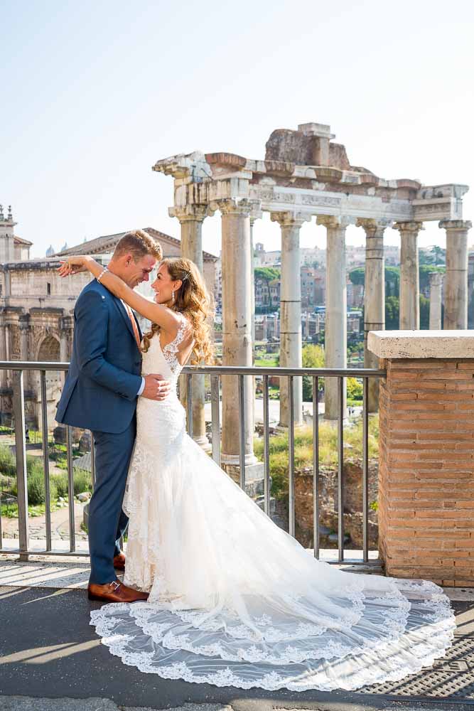 The groom and the bride posing in front of the ancient forum in Rome Italy