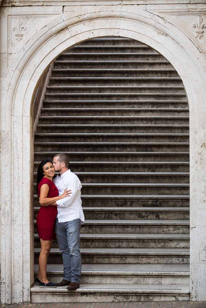 Coupe just engaged posing on a staircase underneath an arch