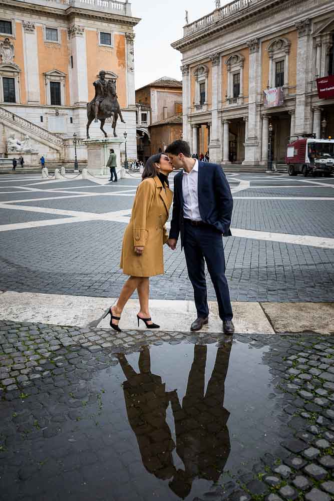 Kissing over a water reflection puddle in the cobble stone streets of Rome