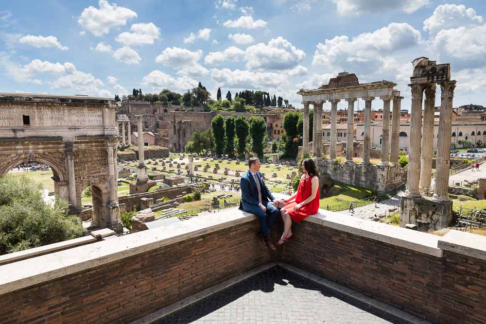 Honeymooners sitting down before the ancient roman site of the foro in Rome Italy