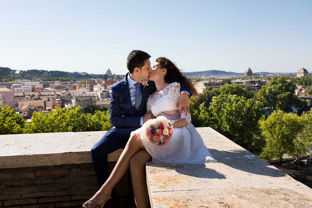 Bride and groom kissing over the roman rooftop view