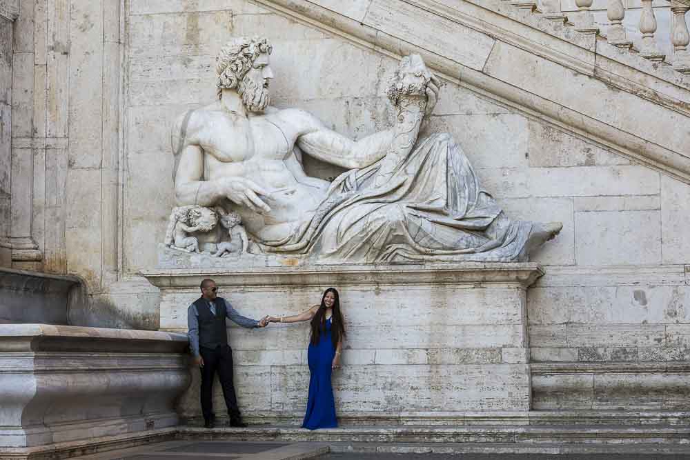 Couple posing underneath an ancient roman statue