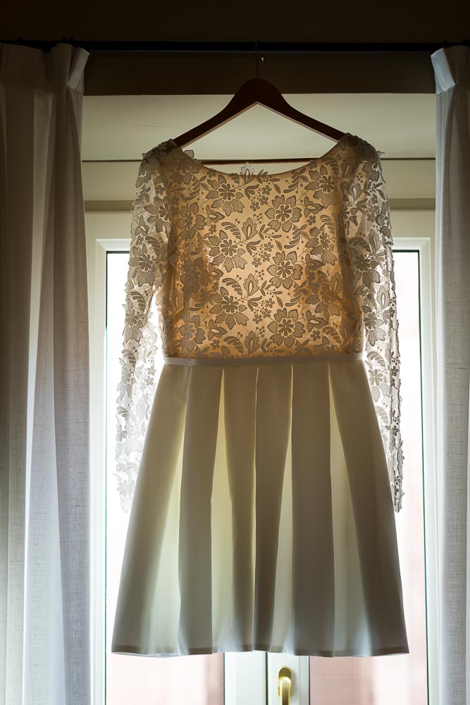 Bridal dress hung from a window to be photographed with light passing through