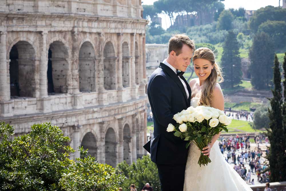 Bride and groom portrait posing by the Roman Colosseum in the far distance. Image by Andrea Matone photographer