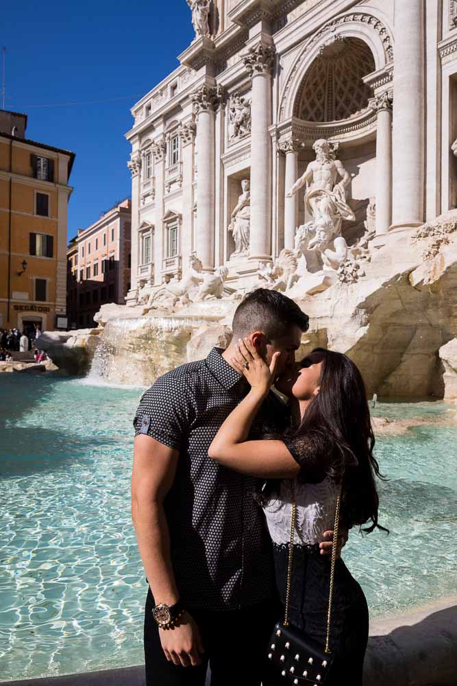 Couple kissing in front of the Trevi fountain after an engagement photoshoot in the late morning or early afternoon 