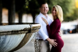 Foreground focus on a water fountain with a couple together in the background out of focus