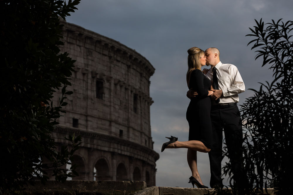 Kissing by the Roman Colosseum at dusk. Portrait photo session in Rome Italy
