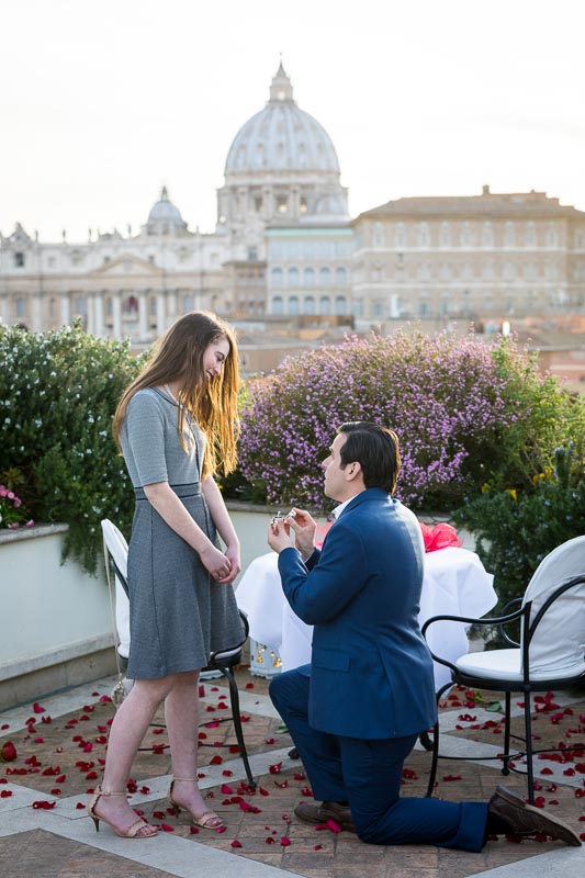 Man proposing marriage on top of a rooftop terrace overlooking the city of Rome from above at sunset