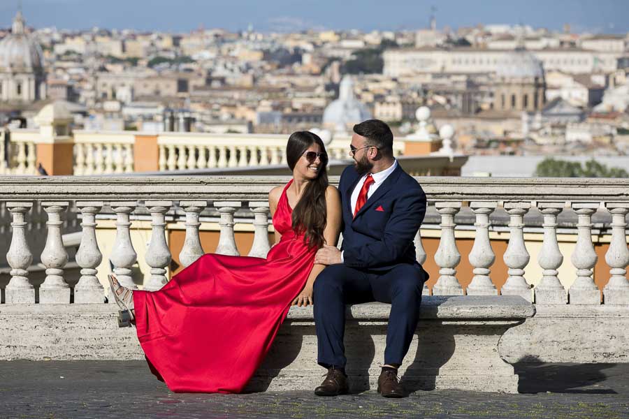 Photo shoot of a couple sitting down on a marble bench overlooking the roman skyline in the background