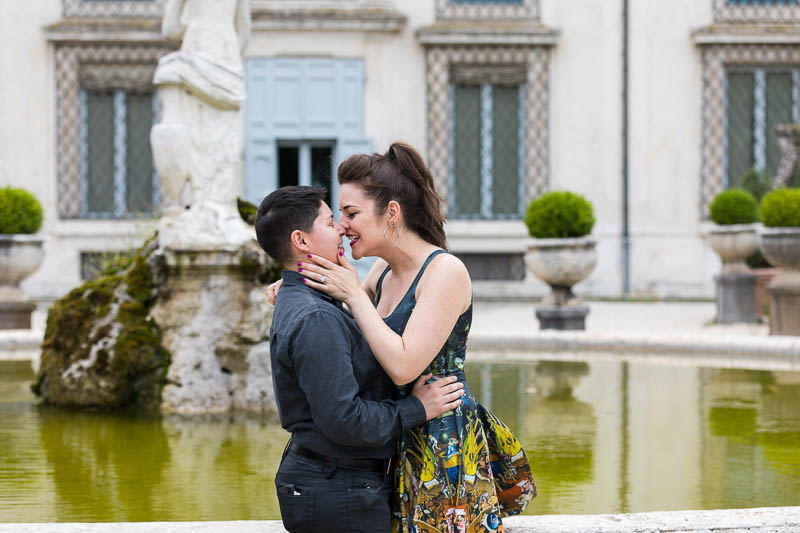 Same sex lesbian couple kissing by a scenic fountain