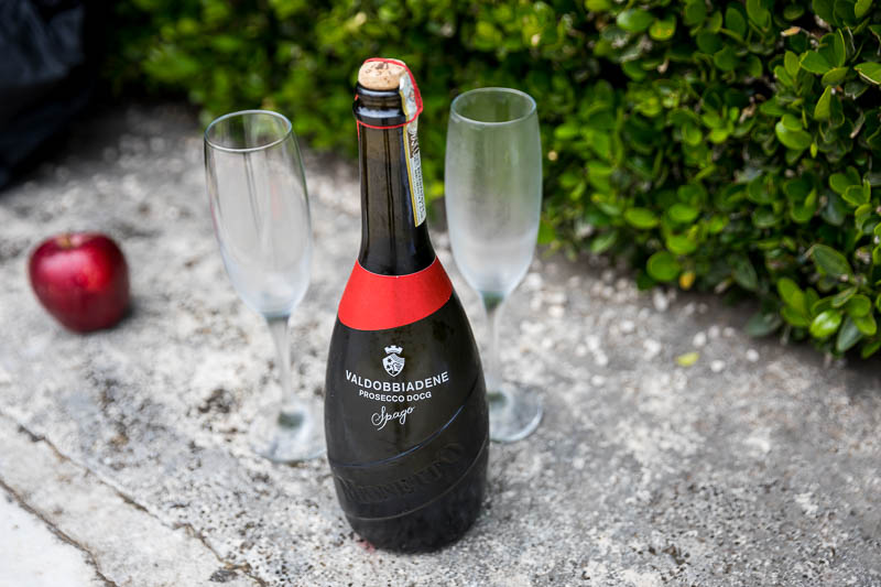 Italian Prosecco wine bottle close up with glass flutes and an apple