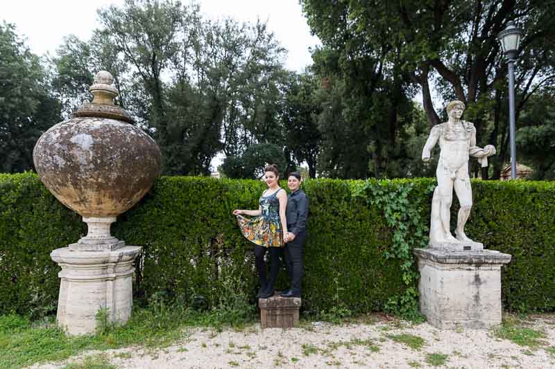 Portrait picture of a gay couple posing next to roman statues