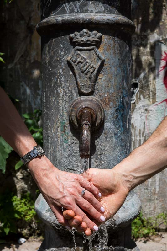 Holding hands together under the water of a fountain. Engaged in Rome