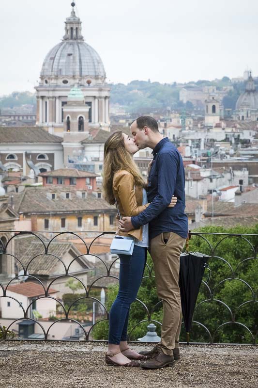 Kissing in love before the panoramic view of the roman rooftops