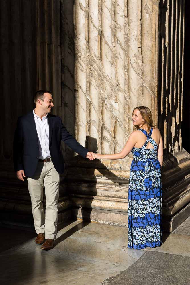 Just engaged walking hand in hand in between ancient columns