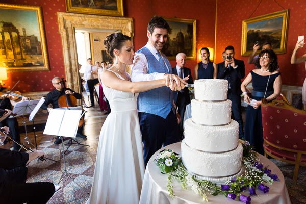 Newlyweds cutting the wedding cake in front of all the guests