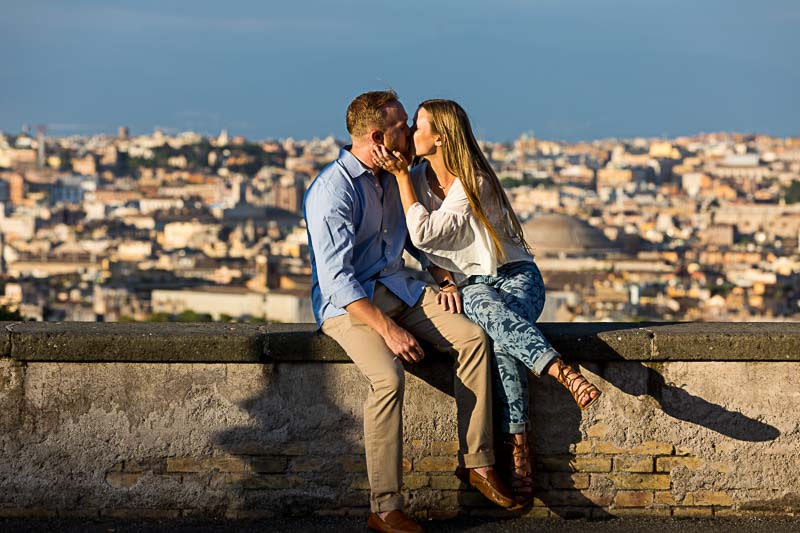 Couple kissing during an engagement session after having proposed overlooking the ancient city from higher terrace ground