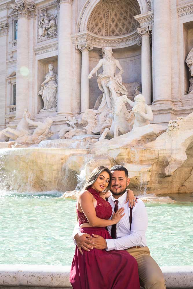 Sitting down portrait images of a couple posing on the water edge of Fontana di Trevi on a nice summer day in Rome 