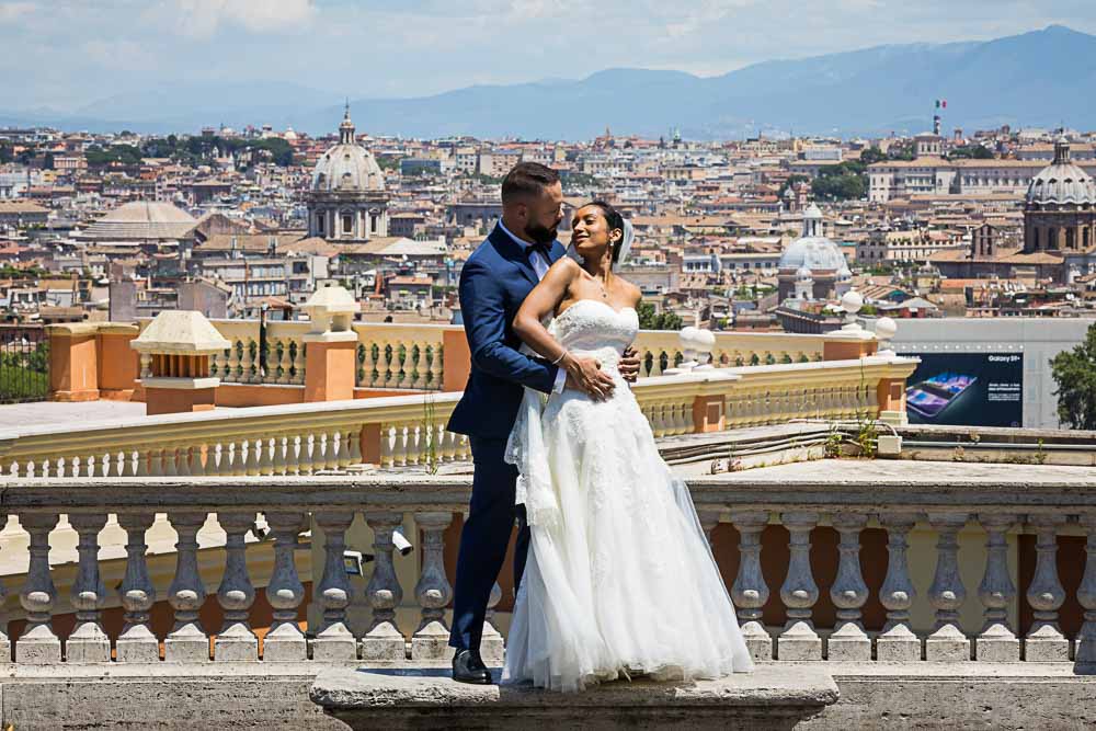 Newlyweds standing before the roman skyline from the Janiculum hill in Rome