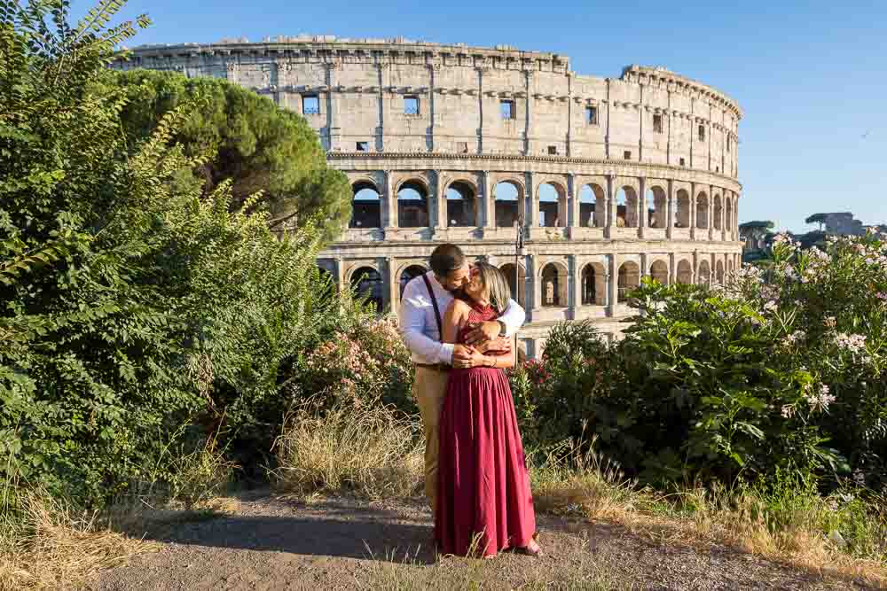 Posing for a portrait picture at the Roman Colosseum. Couple standing together and kissing before one of the main iconic landmarks in Rome