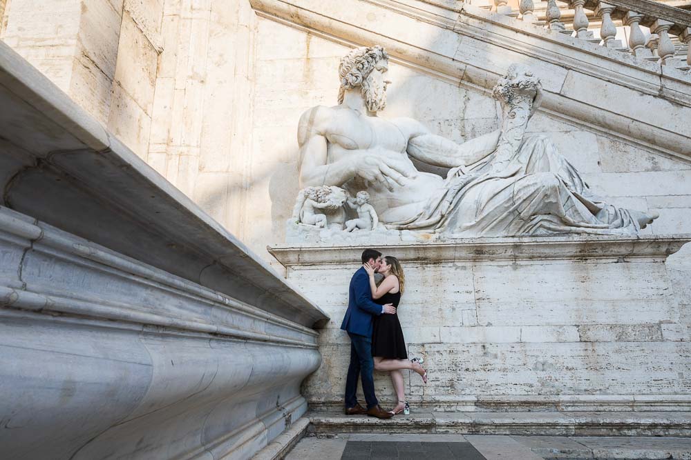 Portrait of a newly engaged couple under a giant marble statue