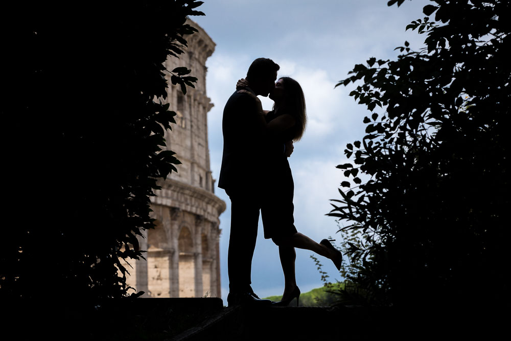 Silhouette image of a couple posing in front of the roman Coliseum in Rome Italy.